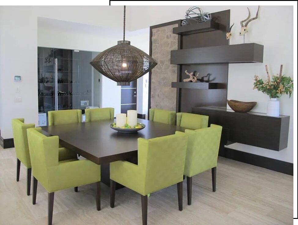 A large square dining table with green chairs